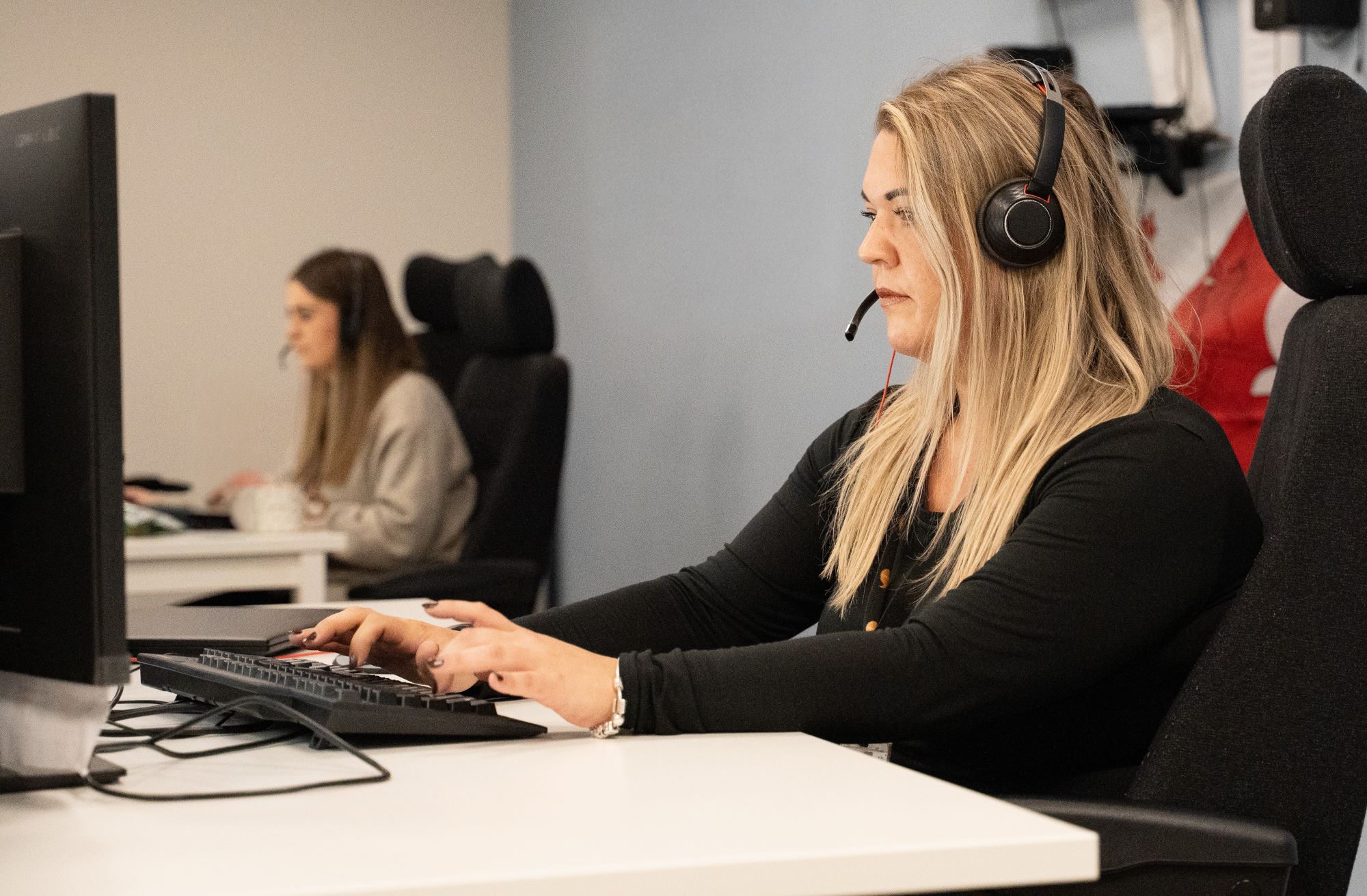 Gweithredwyr canolfan alwadau yn gweithio wrth gyfrifiaduron.