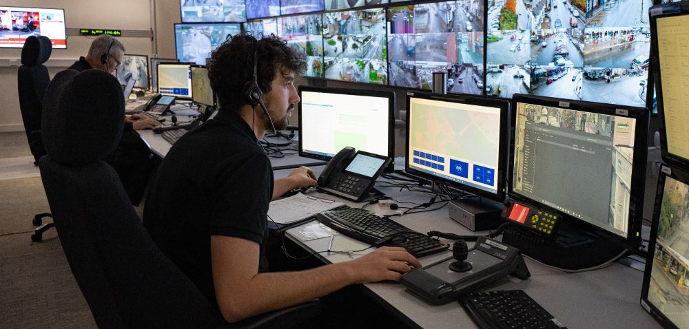 Gweithredwr teledu cylch cyfyng mewn banc o monitorau teledu cylch cyfyng.