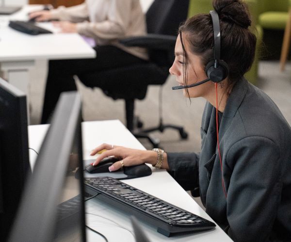 Gweithiwr canolfan alwadau wrth desg.